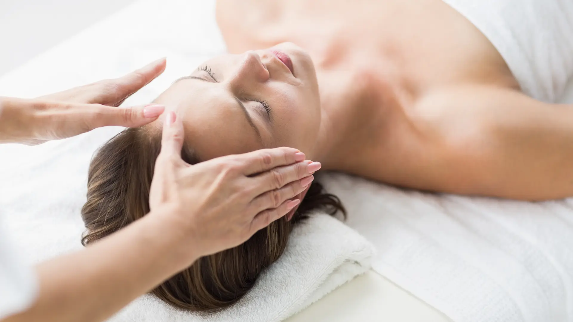 Cropped hands of therapist performing reiki on woman