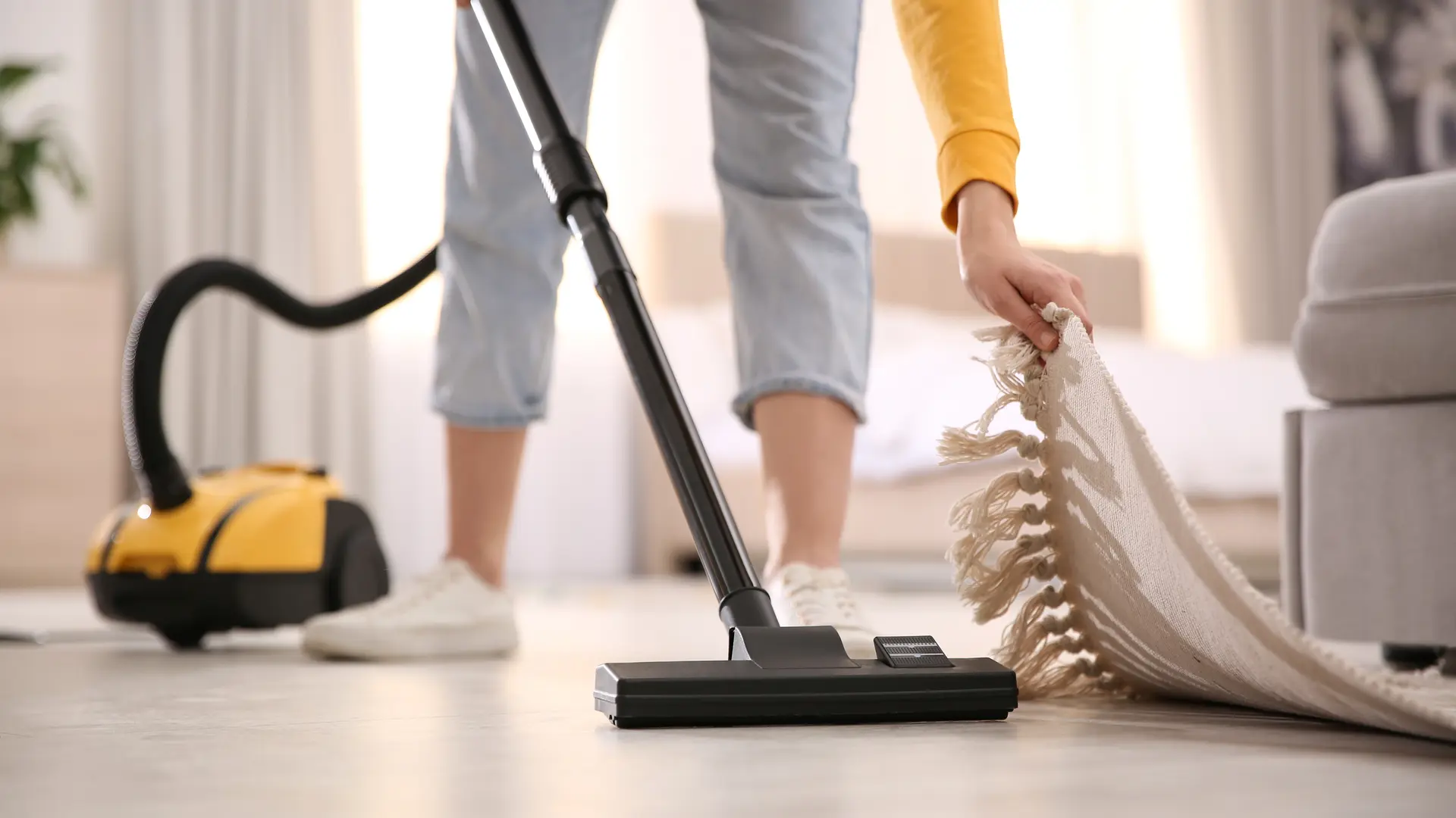 Young woman using vacuum cleaner at home, closeup