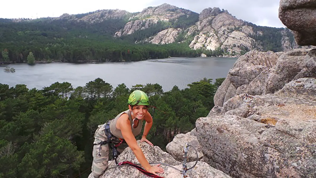 Femme que finit sont escalade, dans le panorama ont peut apercevoir le lac de l'Ospédale entouré de pins