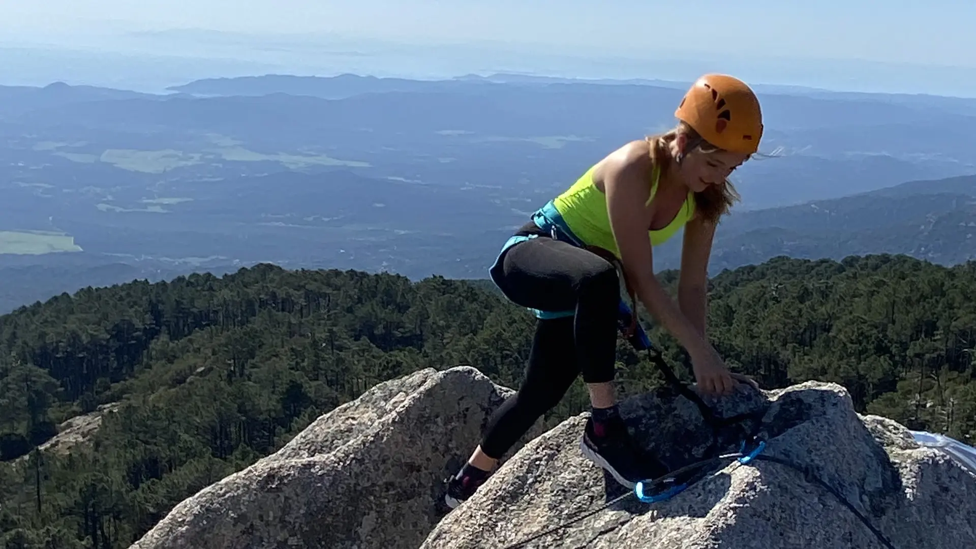 Photo d'une femme en pleine escalade avec vue panoramique sur la forêt de l'Ospedale et le littoral