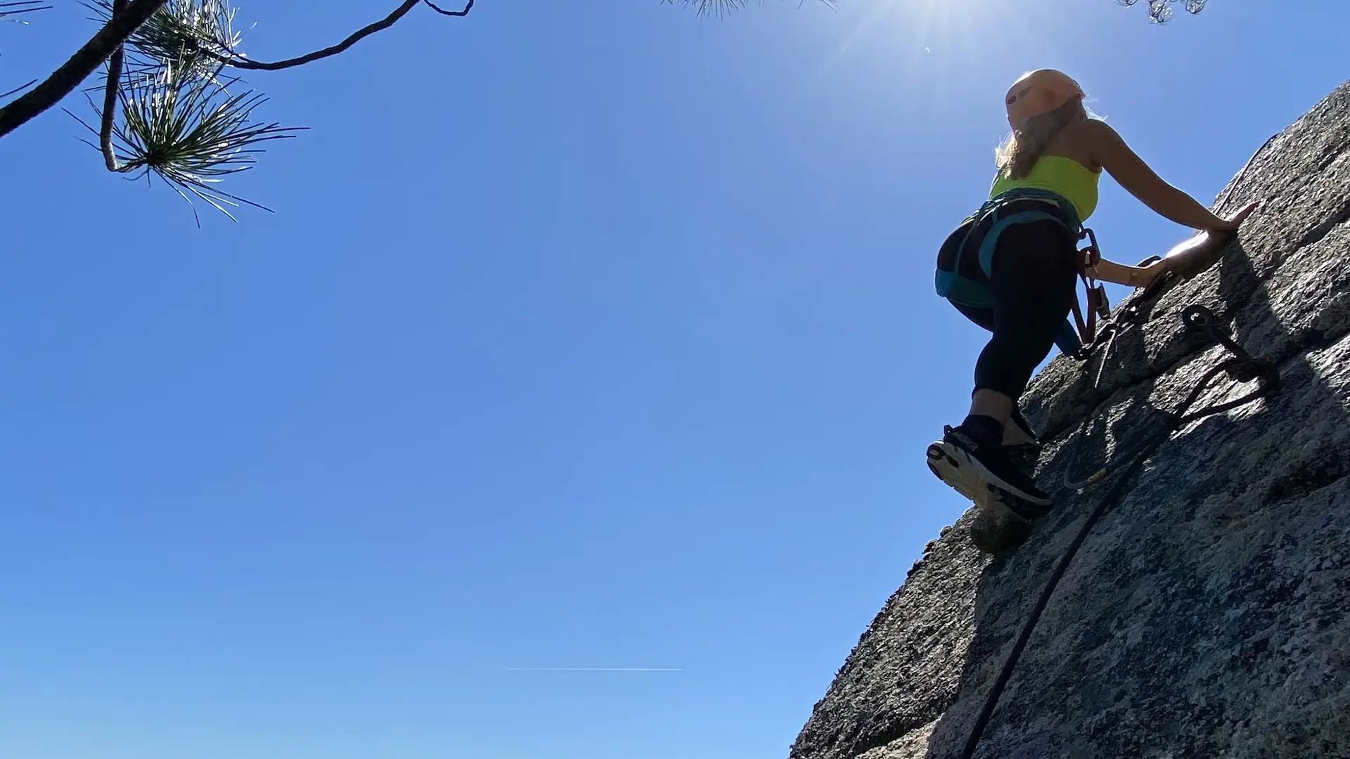 Escalade d'une paroi rocheuse par une femme avec une vue panoramique sur le littoral en arrière plan