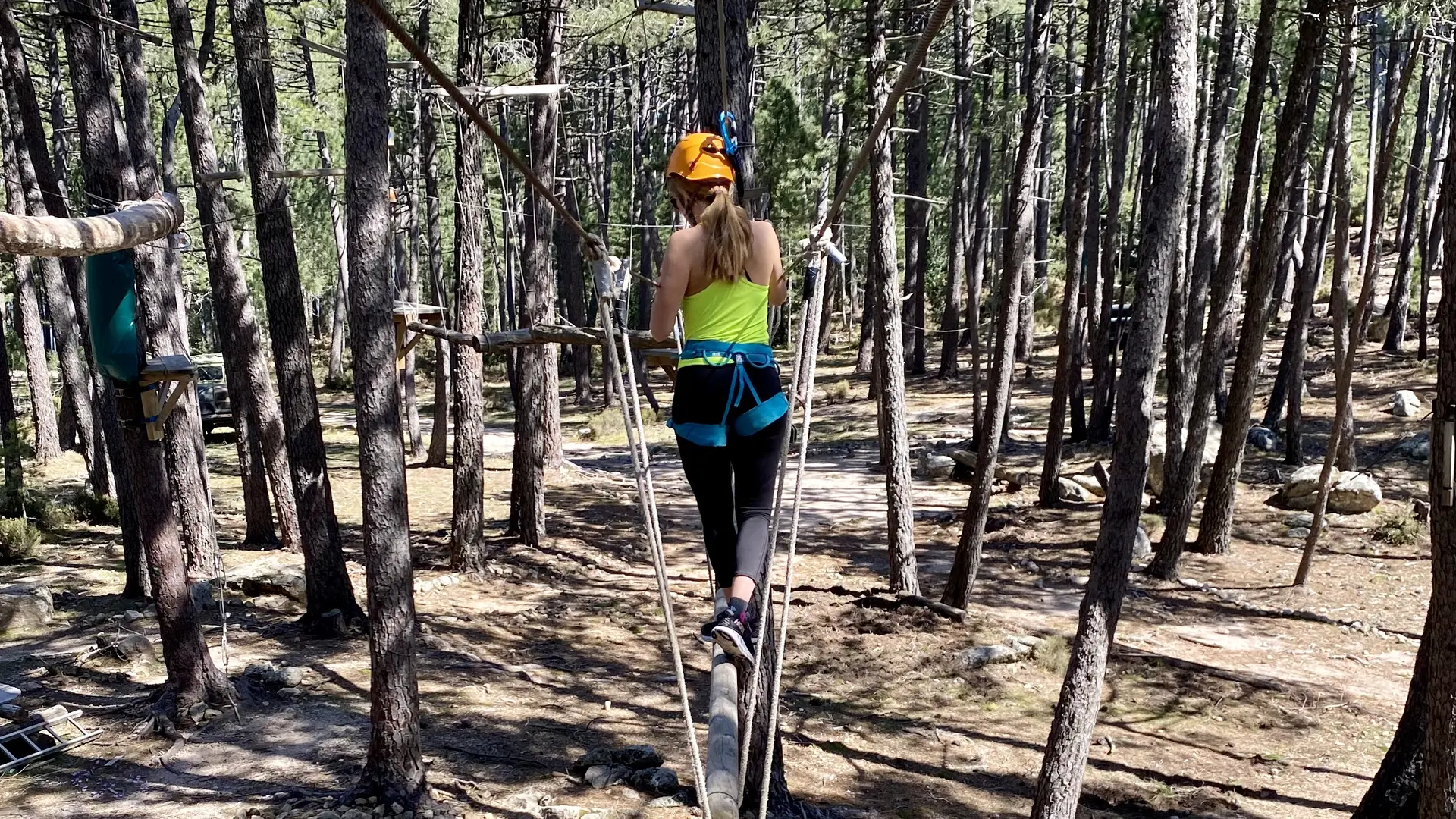 Photo d'une femme pendant une session d'accrobranche au cœur de la forêt  de pins