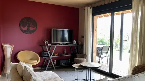 Le salon avec baie vitrée qui donne sur la terrasse couverte et le jardin.