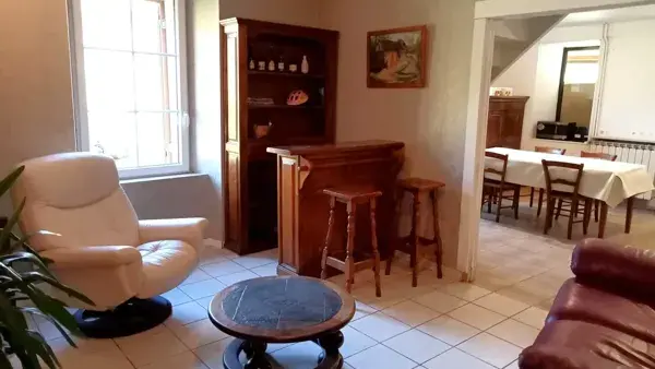 Vaste salon avec : bar, TV et fauteuils en cuir.