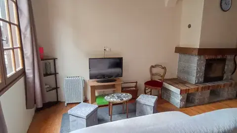 Séjour chaleureux avec cheminée et télévision, idéal pour des moments conviviaux en famille ou entre amis.