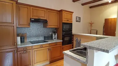 Cuisine ouverte équipée avec four, plaques de cuisson et bar en granit donnant sur le séjour