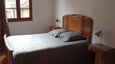 Chambre lumineuse avec lit double en bois et tables de chevet, idéale pour un séjour confortable