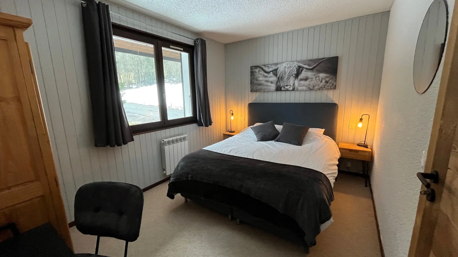 Chambre avec lit deux personnes, grande fenêtre et coin bureau