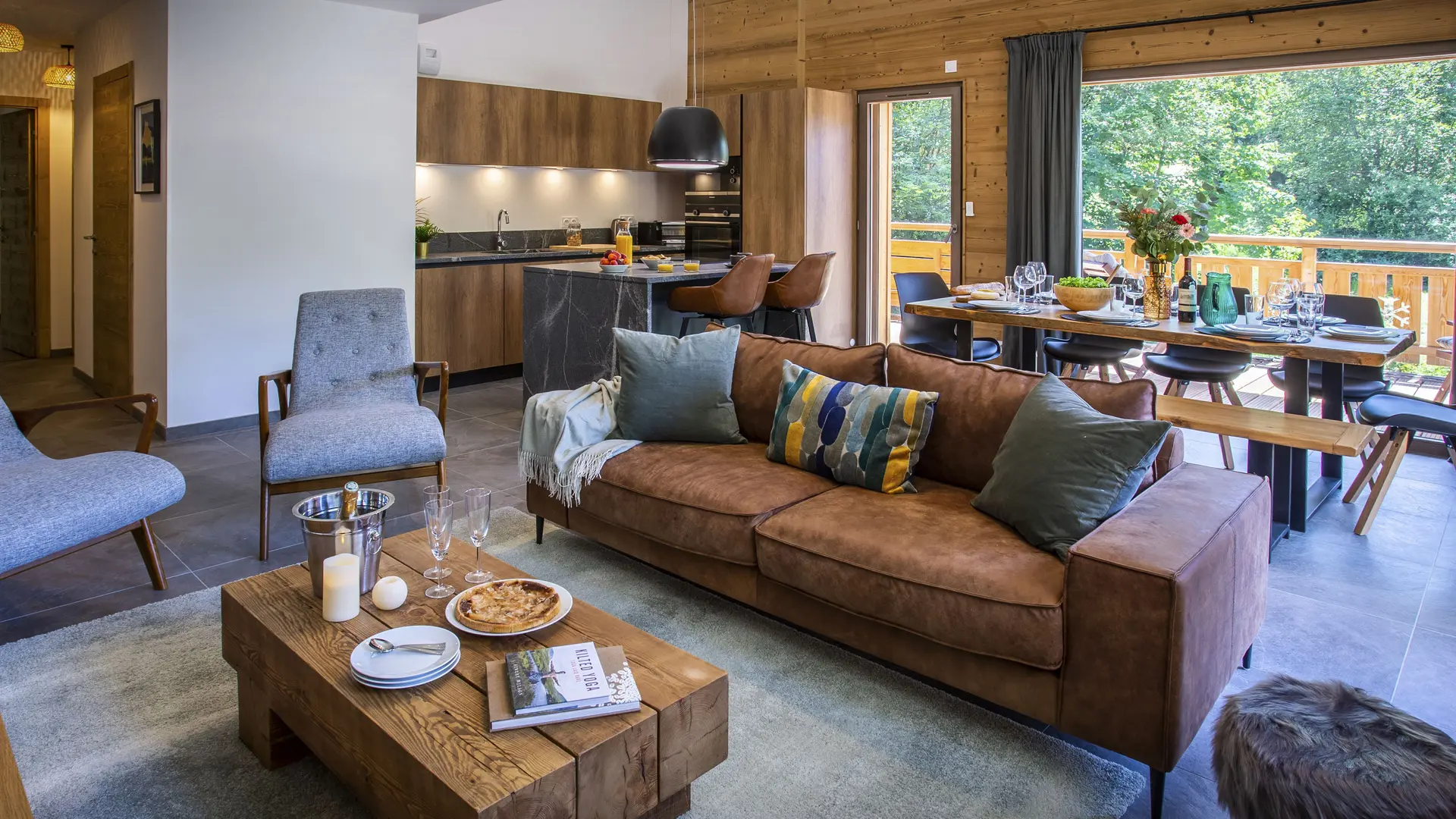 Vue du séjour depuis la partie salon avec l'espace salle à manger et la cuisine en arrière plan