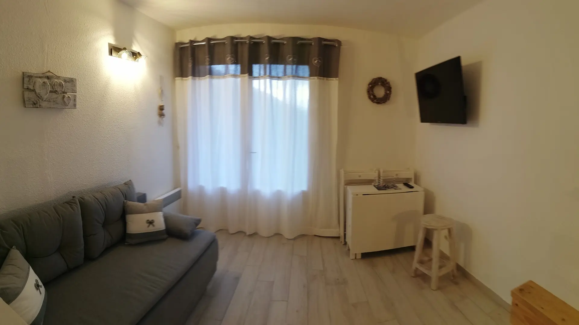 salon lumineux avec canapé, télévision, porte-fenêtre