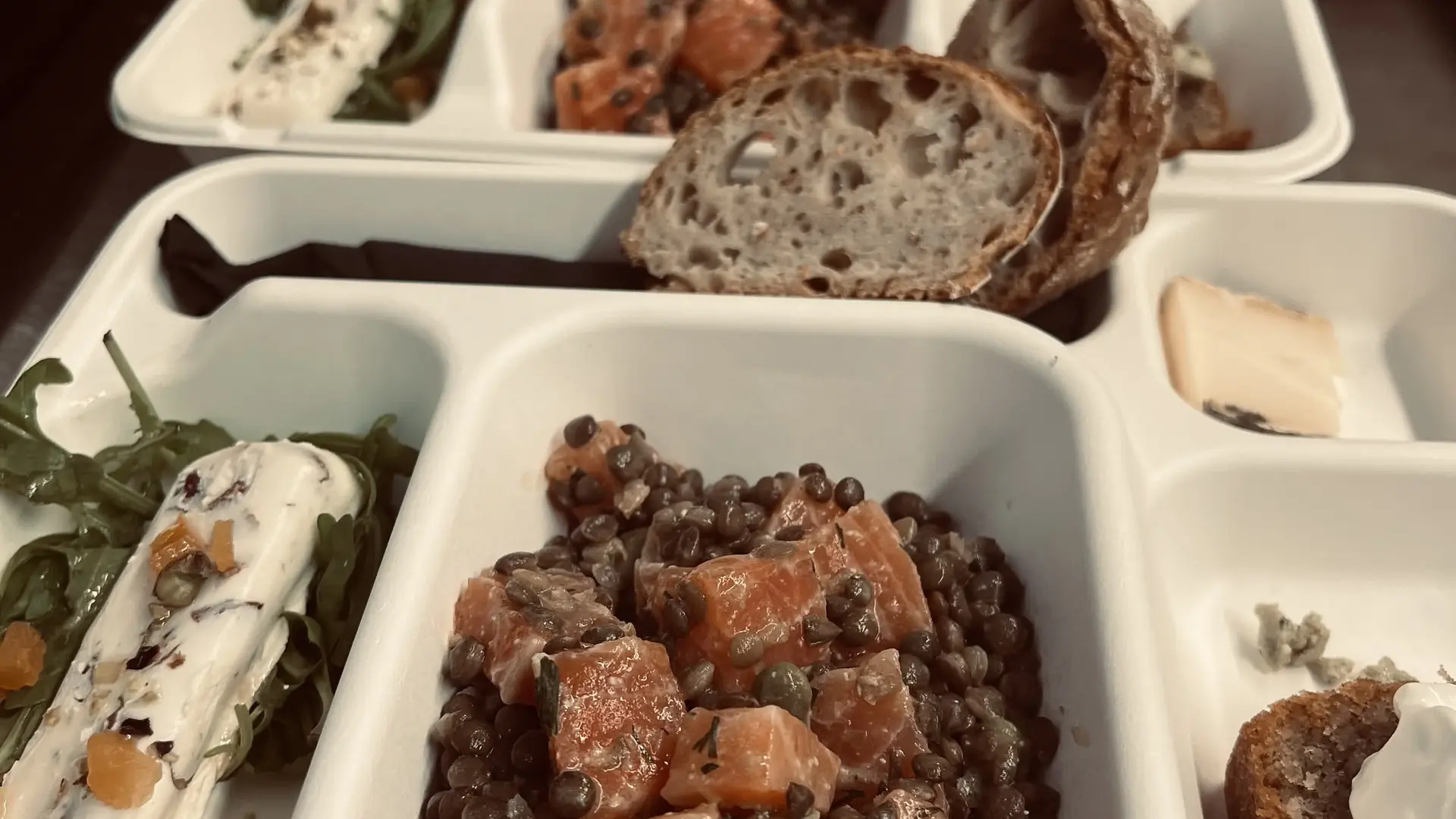 Plateaux repas appétissants composés de lentilles, saumon, fromage et pain.