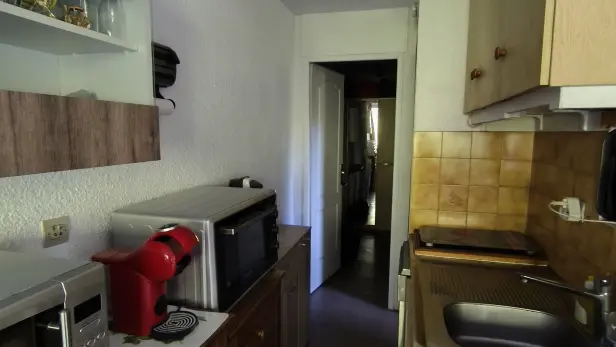Vue générale de la cuisine équipée avec micro-onde et four combiné, plaques de cuisson