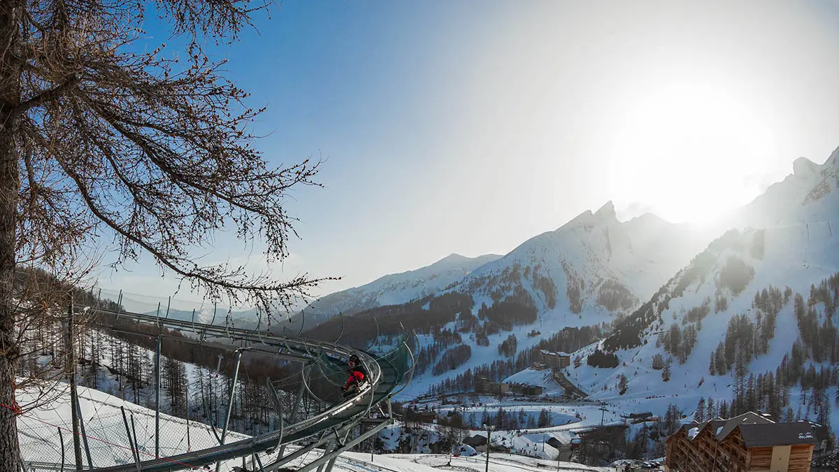 Luge sur rail Verdon Express, nacelle deux places, série de virages en épingle dans un paysage enneigé, vue dégagée sur les montagnes enneigées environnantes