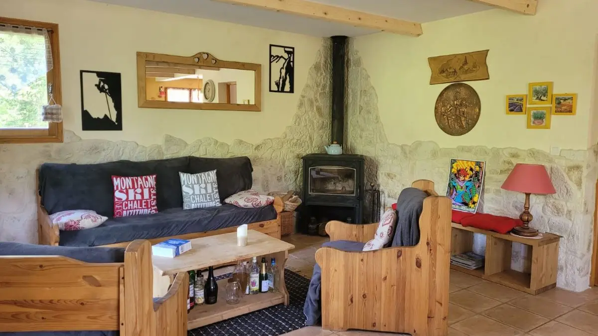 Séjour lumineux et confortable avec canapé, fauteuils, table basse, poêle à bois, carrelage au sol