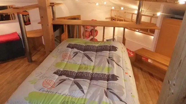 Cette chambre se trouve sous les combles sur une mezzanine. Un lit double occupe le centre de la pièce. Des escaliers en bois mènent à cet espace surélevé.