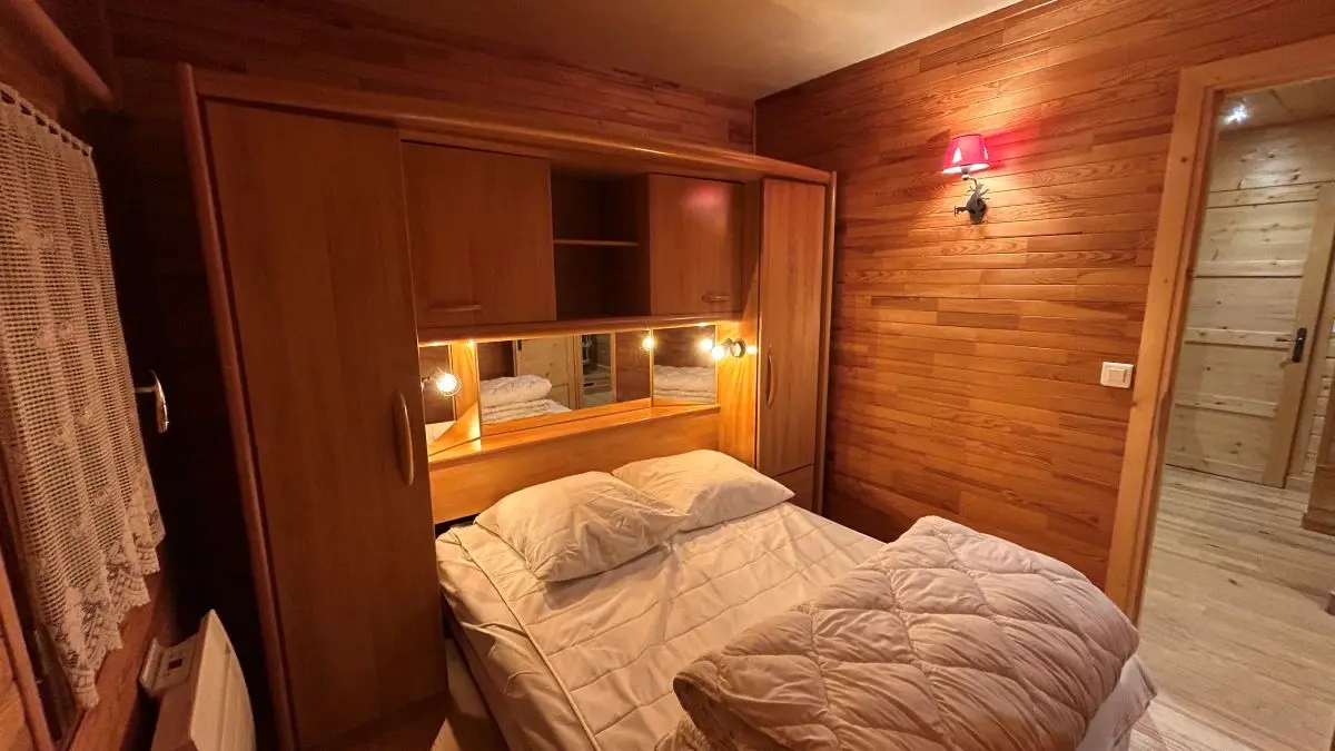 Large bedroom with double bed, wooden furniture, parquet flooring, window