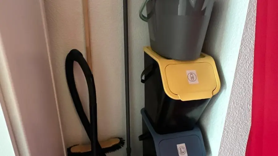 Le coin ménage et recyclage est masqué par un rideau.