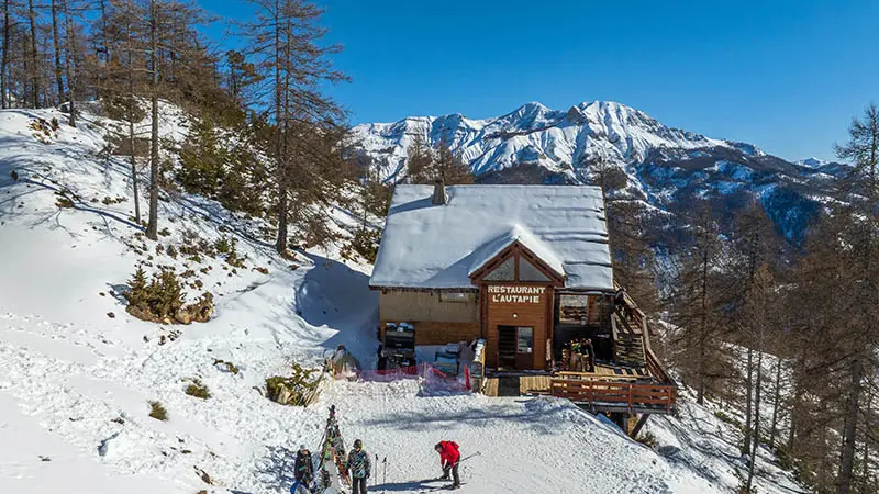 Vue du restaurant d'altitude, chalet en bois et pierre au milieu des montagnes enneigées, terrasse en bois