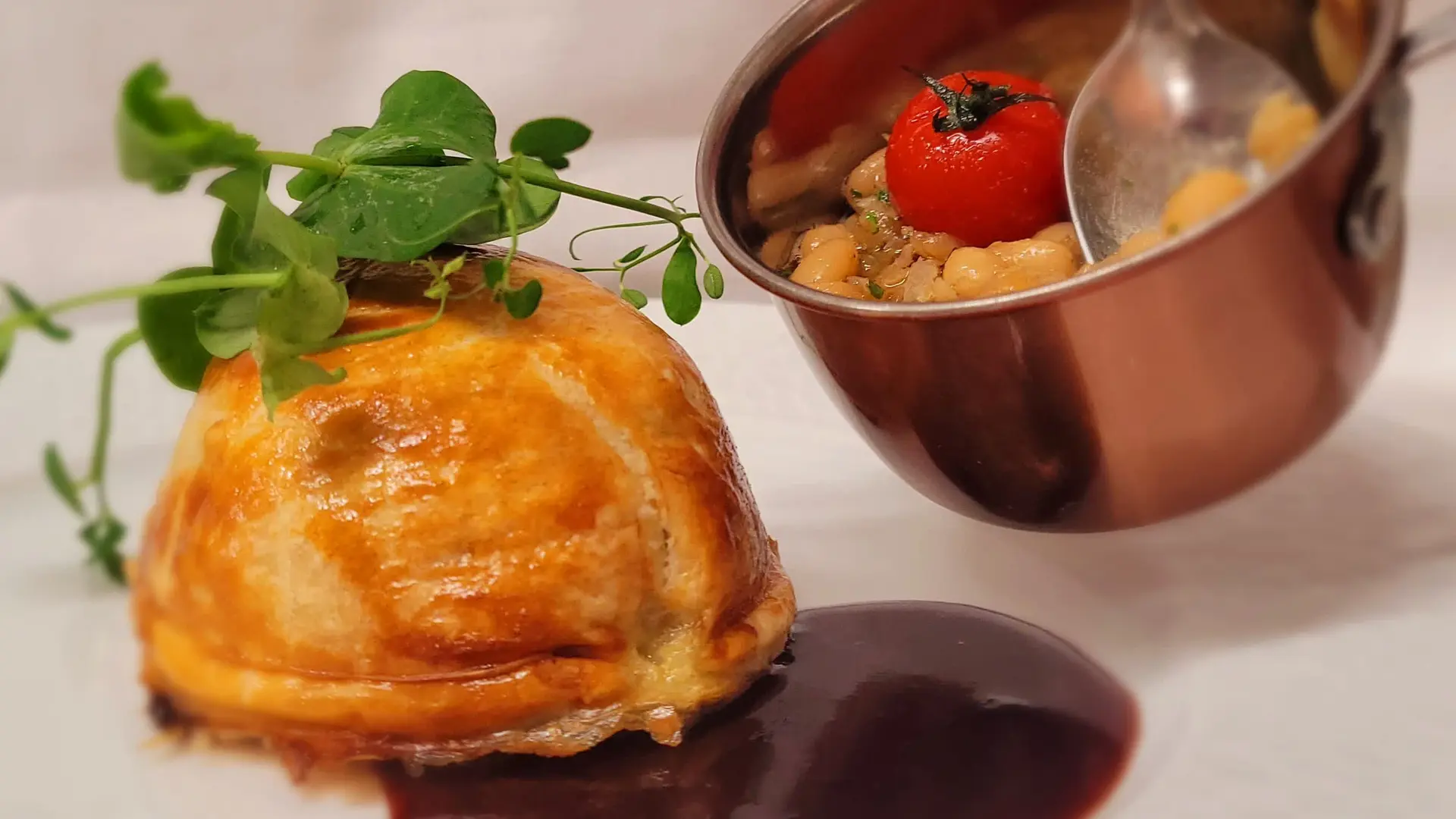 Un plat raffiné composé d’un feuilleté doré servi avec une sauce onctueuse et des légumes mijotés.