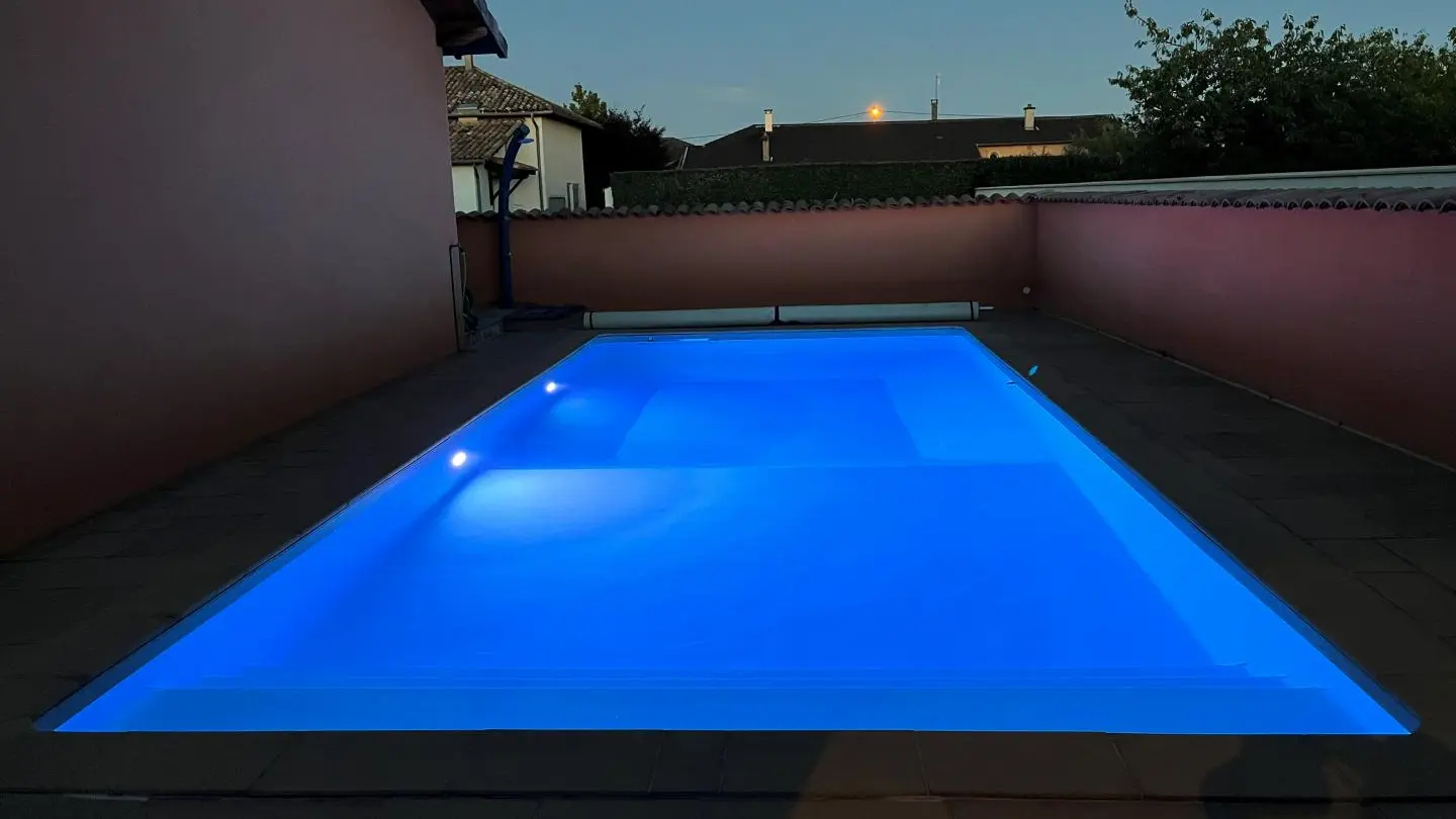 Vue sur la piscine depuis la terrasse à la tombée de la nuit.