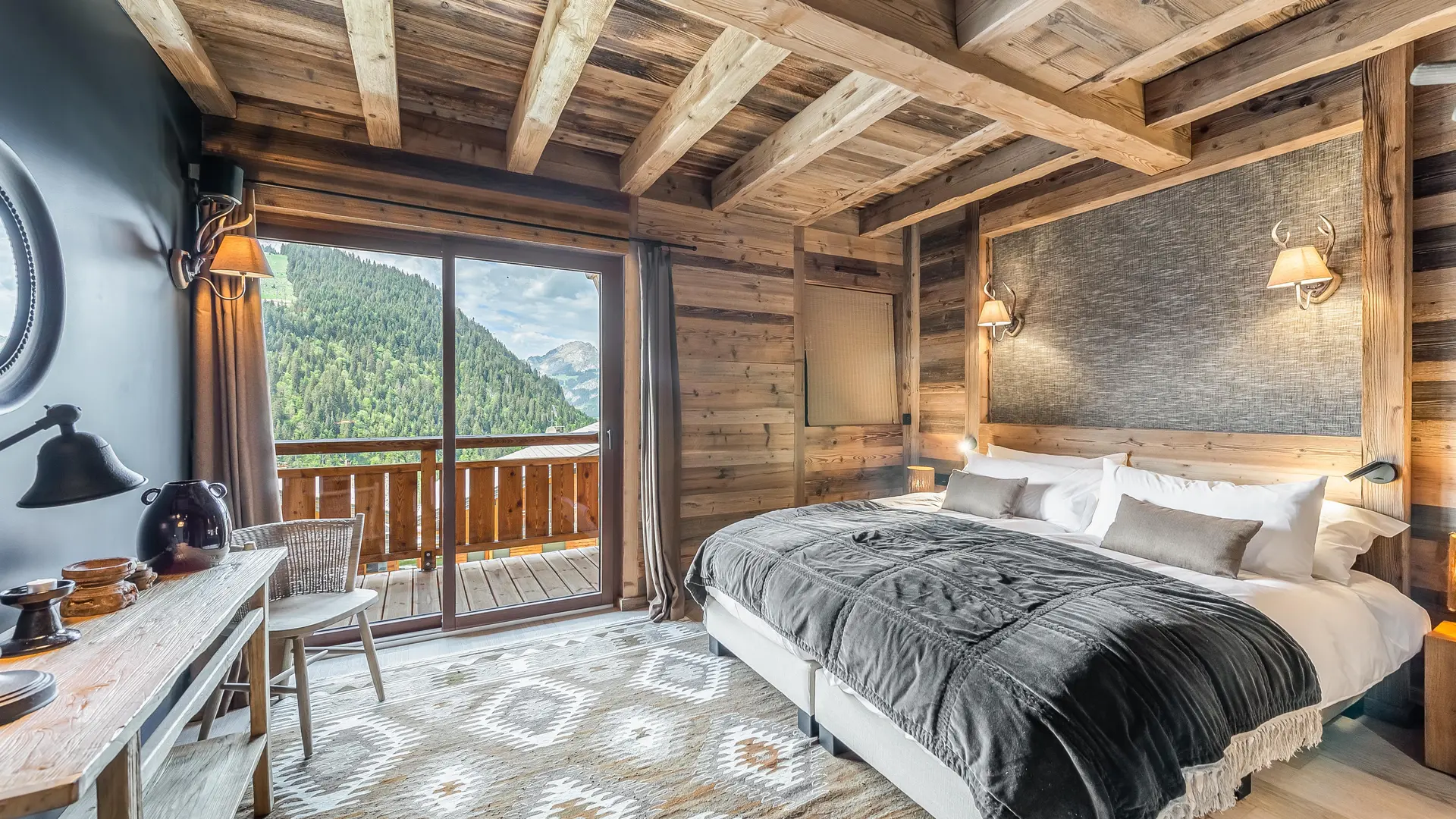 Chambre double avec poutres apparentes décoration et ameublement moderne, accès balcon par grande baie vitrée