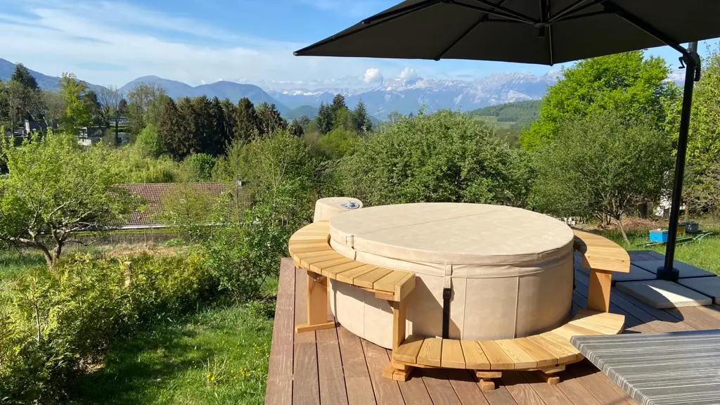 Jacuzzi couvert sur une terrasse avec un panorama sur les montagnes alentours.