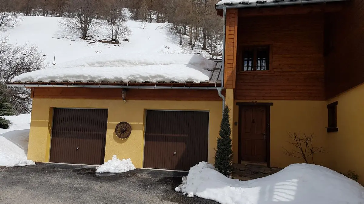 Côté du chalet, porte d'entrée et deux garages