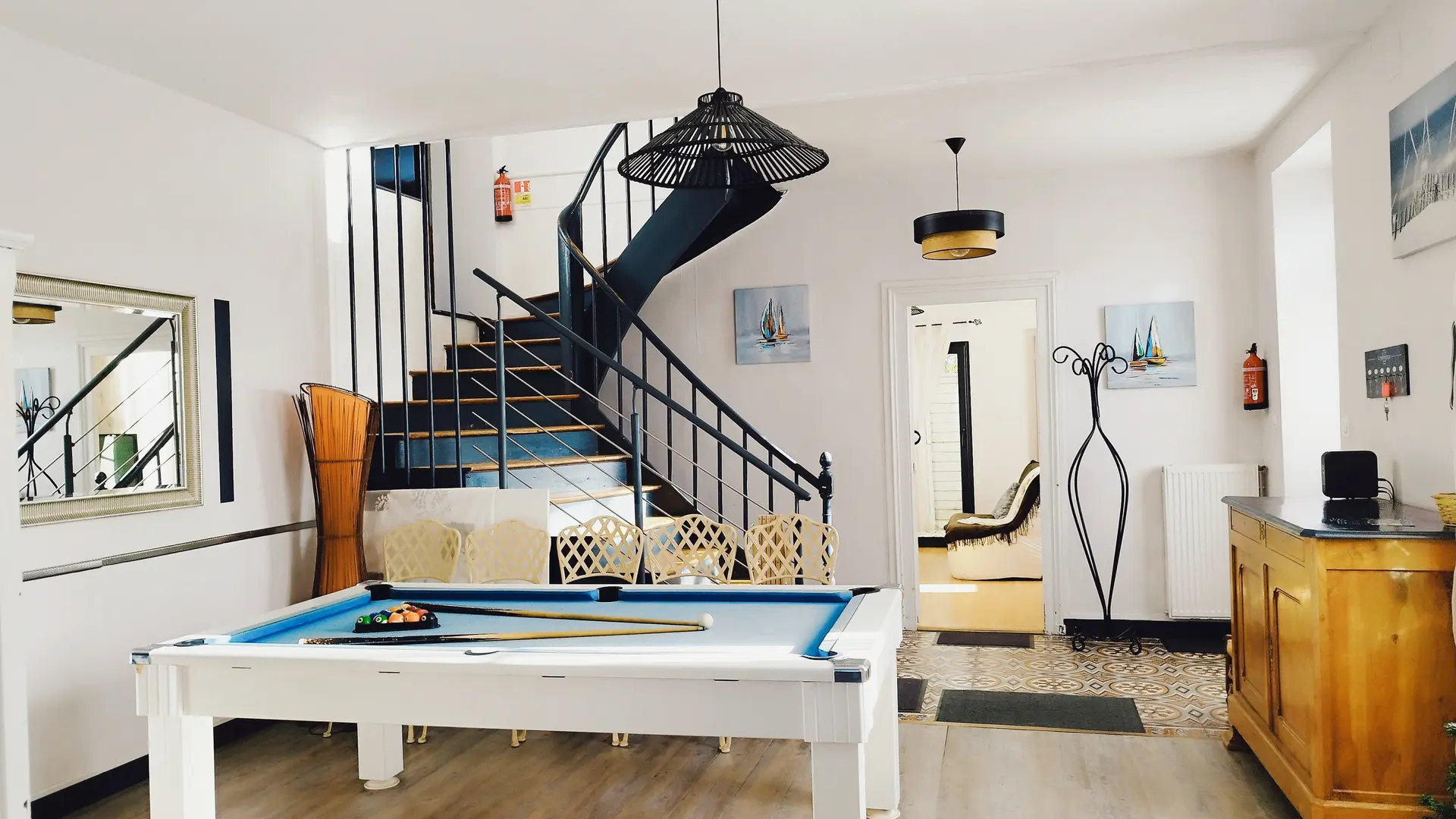 Salon avec billard, buffet, escalier vers l'étage.