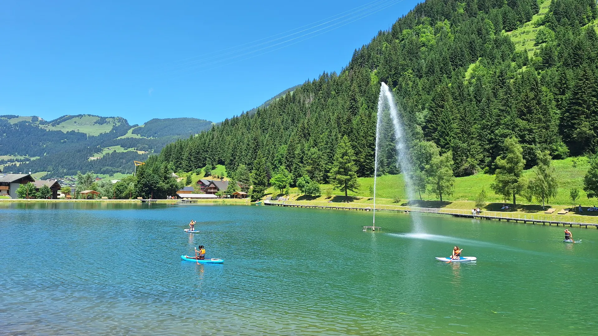 Vue sur Lac de Vonnes à Châtel en été avec paddles et jet d'eau sous le ciel bleu