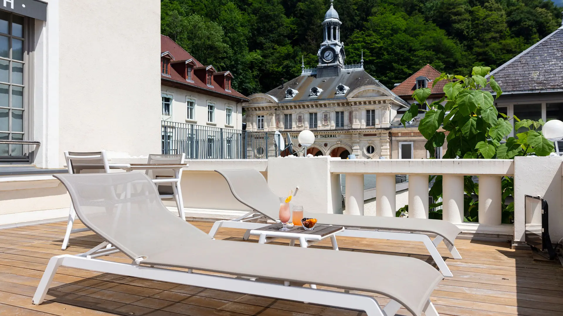 Cette terrasse privative offre un espace de détente avec des chaises longues confortables et une vue sur les thermes d'Uriage.