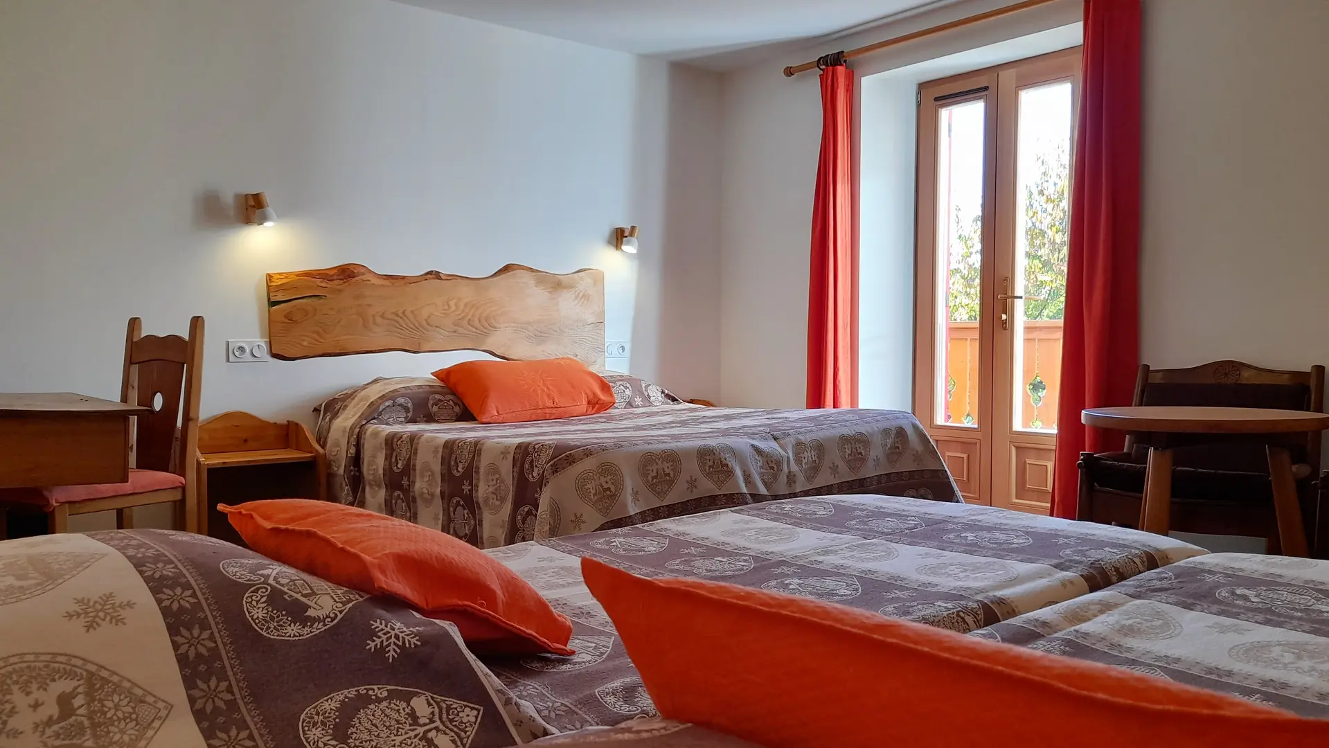 Chambre comprenant un lit double, deux lits simples, un bureau et une table