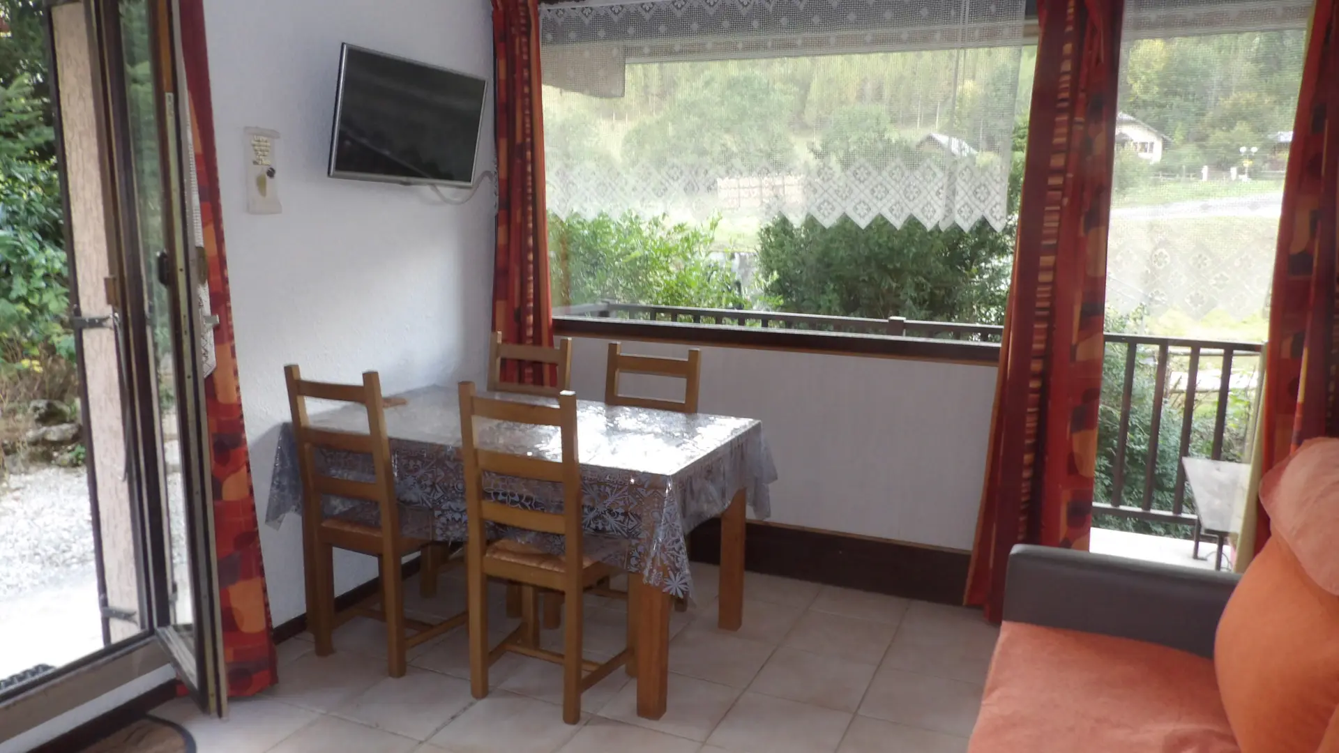 Coin séjour avec un canapé et une table pour 4 personnes, avec accès à la terrasse et au balcon