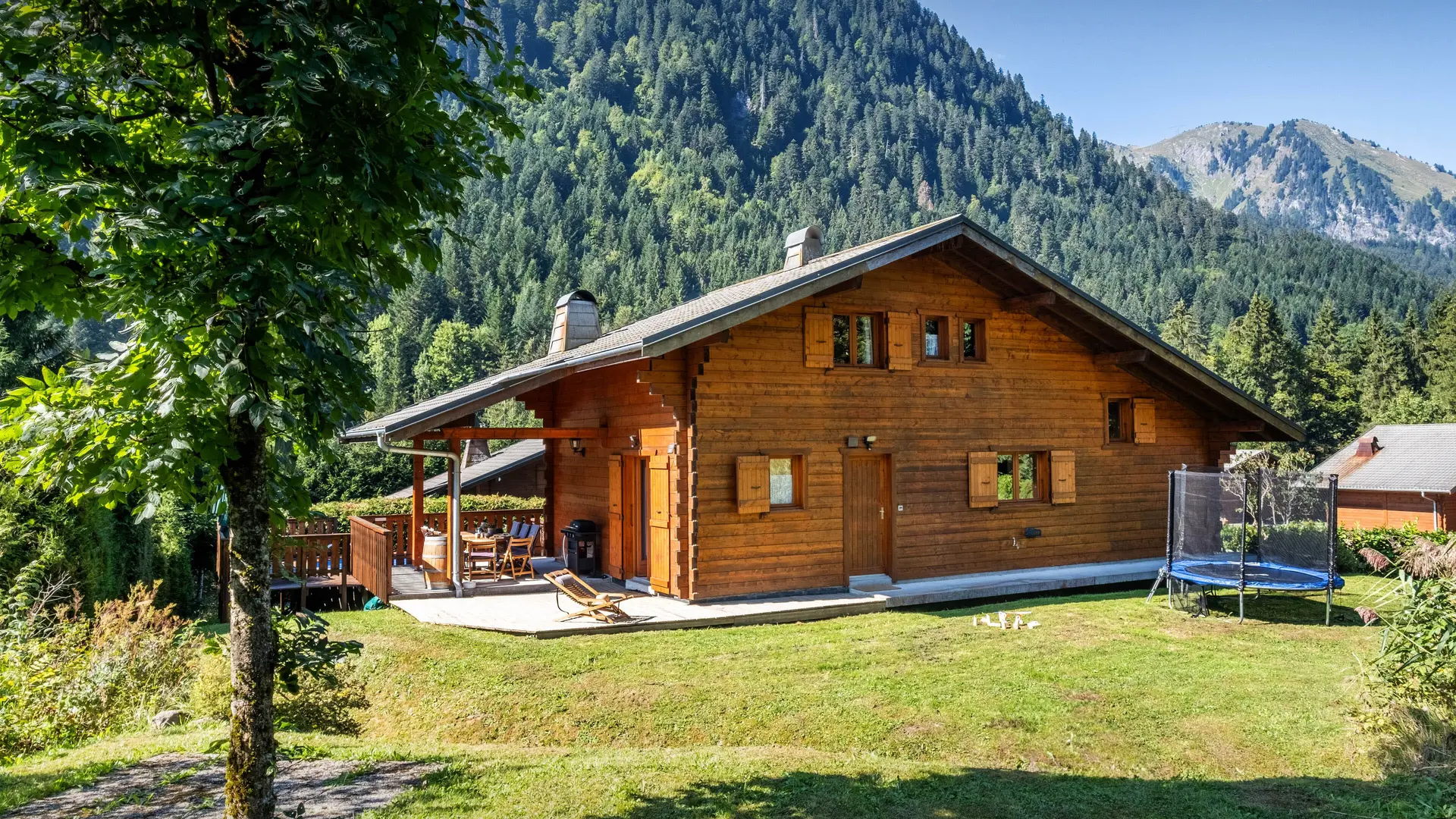 Arrière du chalet avec trampoline et terrain ombragé