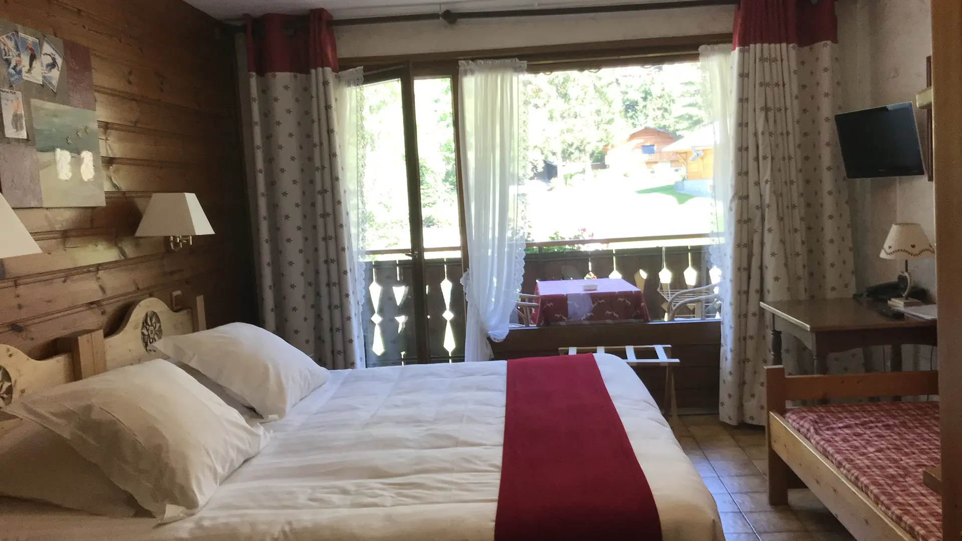 Chambre avec lit double, banquette, table, télévision, balcon avec table et chaises