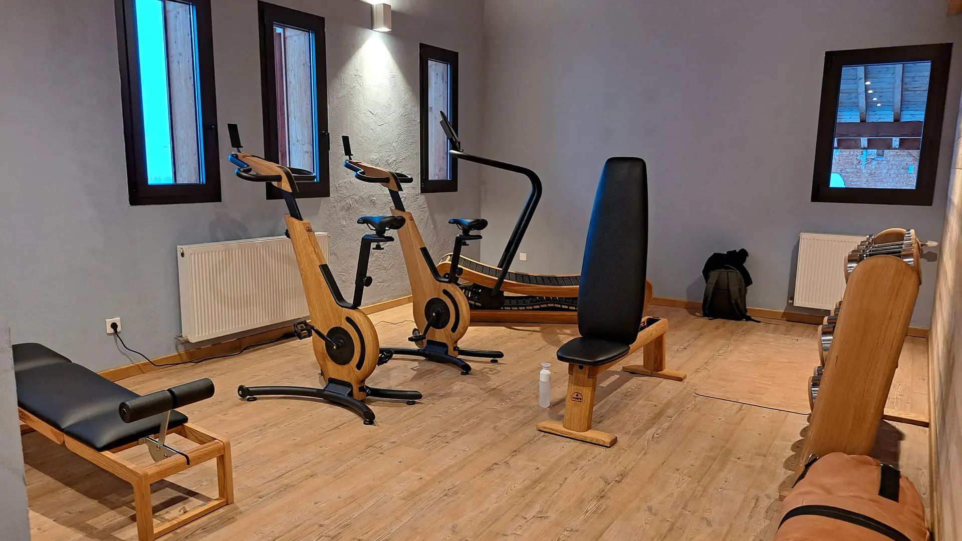 A modern gym equipped with designer wooden equipment on a light wooden floor.