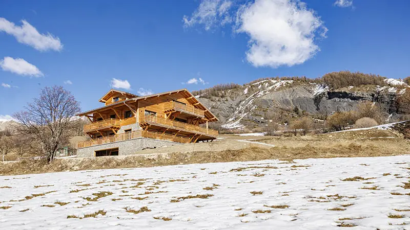 Vue extérieure d'un chalet en bois et pierre de trois étages, paysage montagnard enneigé