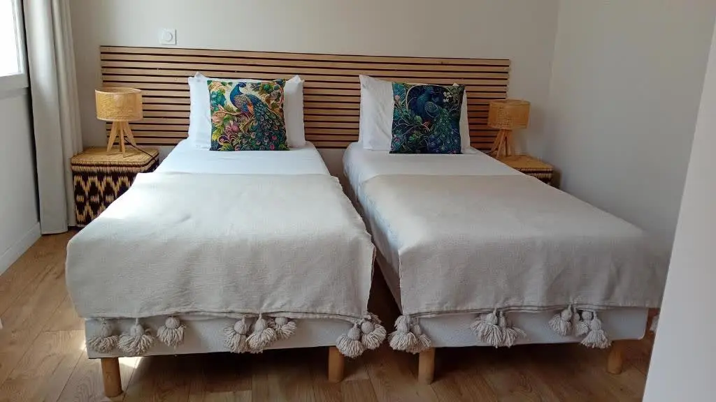 Une chambre accueillante et lumineuse, sublimée par des textiles doux et une tête de lit en bois au style contemporain.