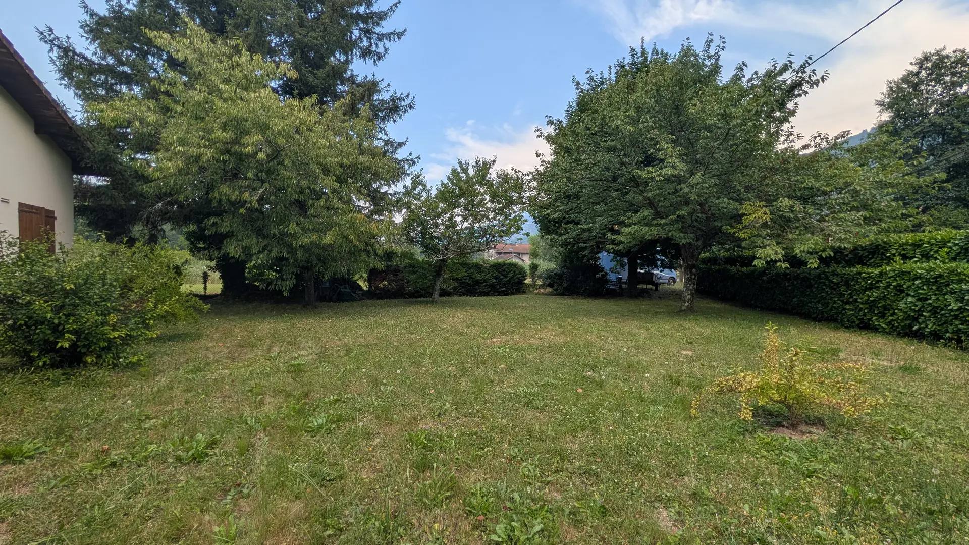 Un grand jardin arboré avec une pelouse verdoyante.
