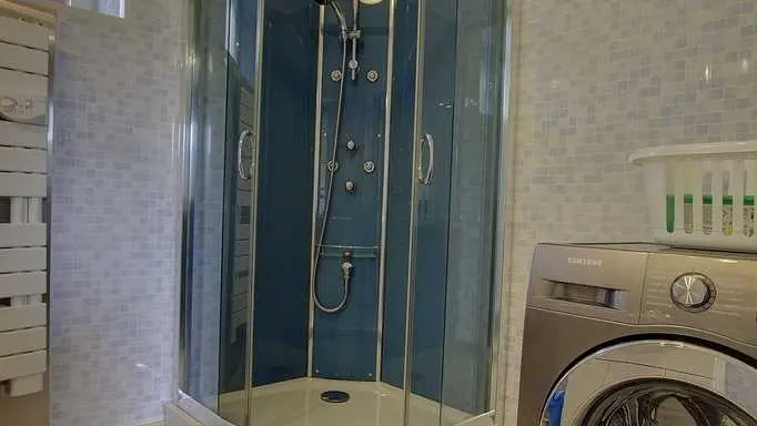 Salle de bain avec douche, évier et machine à laver à disposition