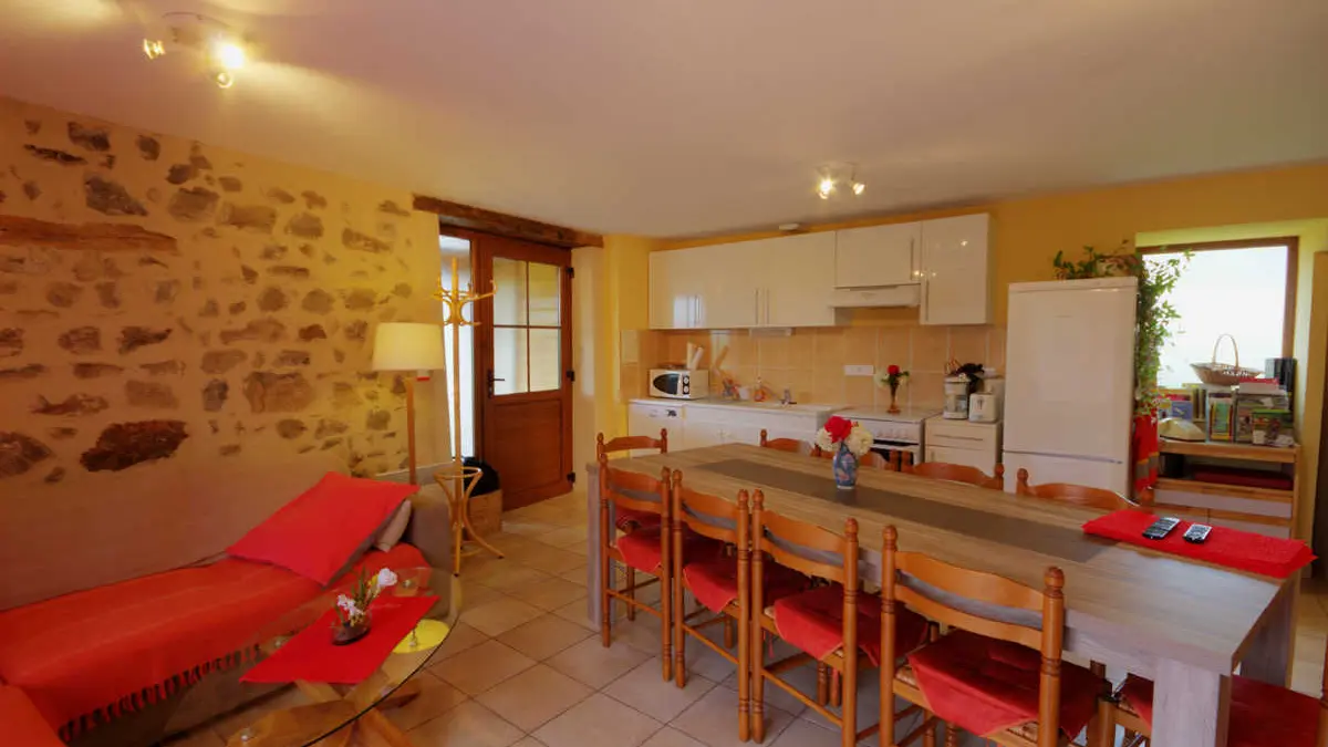 Coin salon, salle à manger et cuisine où se trouve la porte d'entrée.