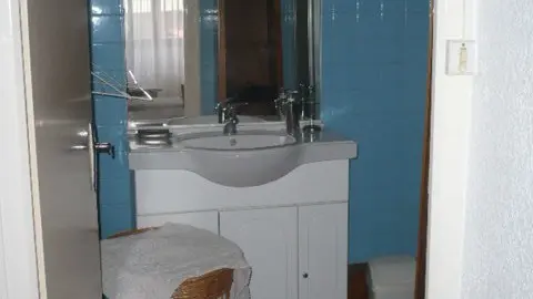 Salle de bain avec un meuble vasque blanc et du carrelage bleu.