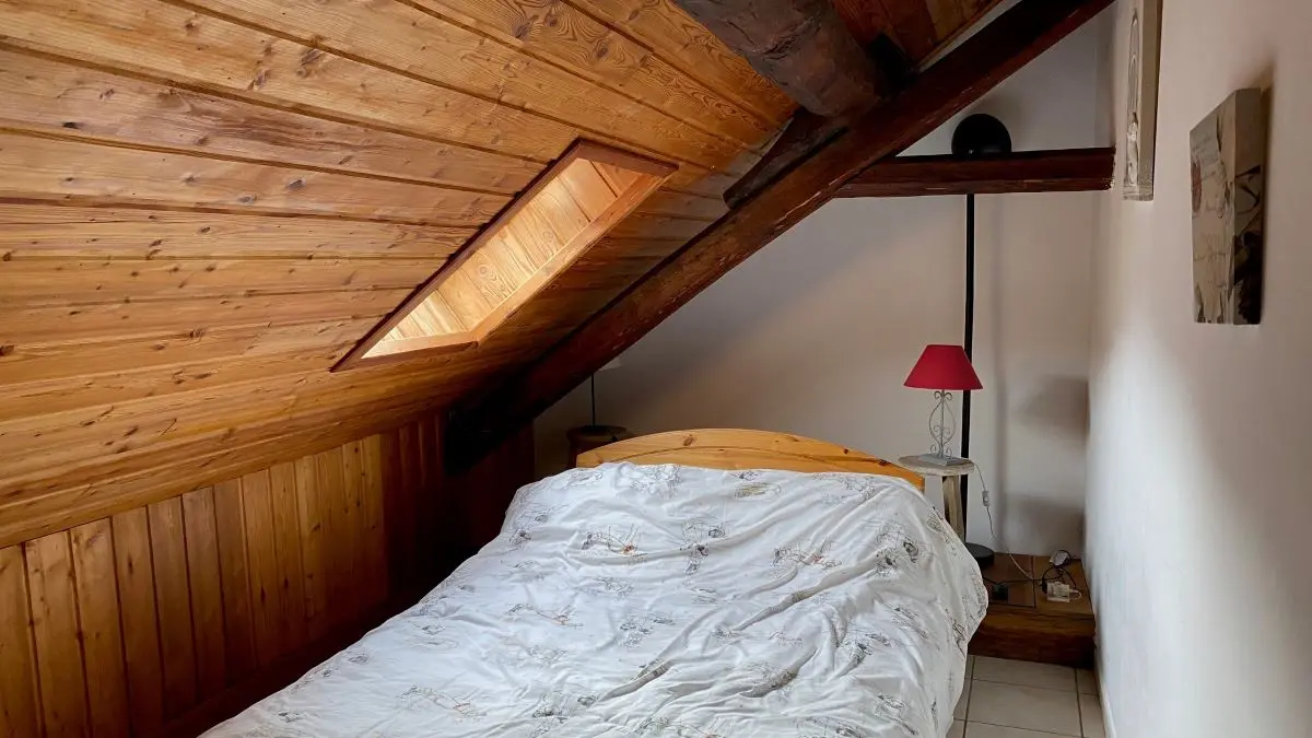 Attic bedroom with double bed, tiled floor, wooden furniture