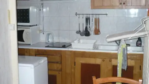 Cette cuisine, équipée d'armoires en bois clair et d'électroménager (lave-linge), offre un espace fonctionnel pour préparer les repas et dispose d'un coin repas attenant.