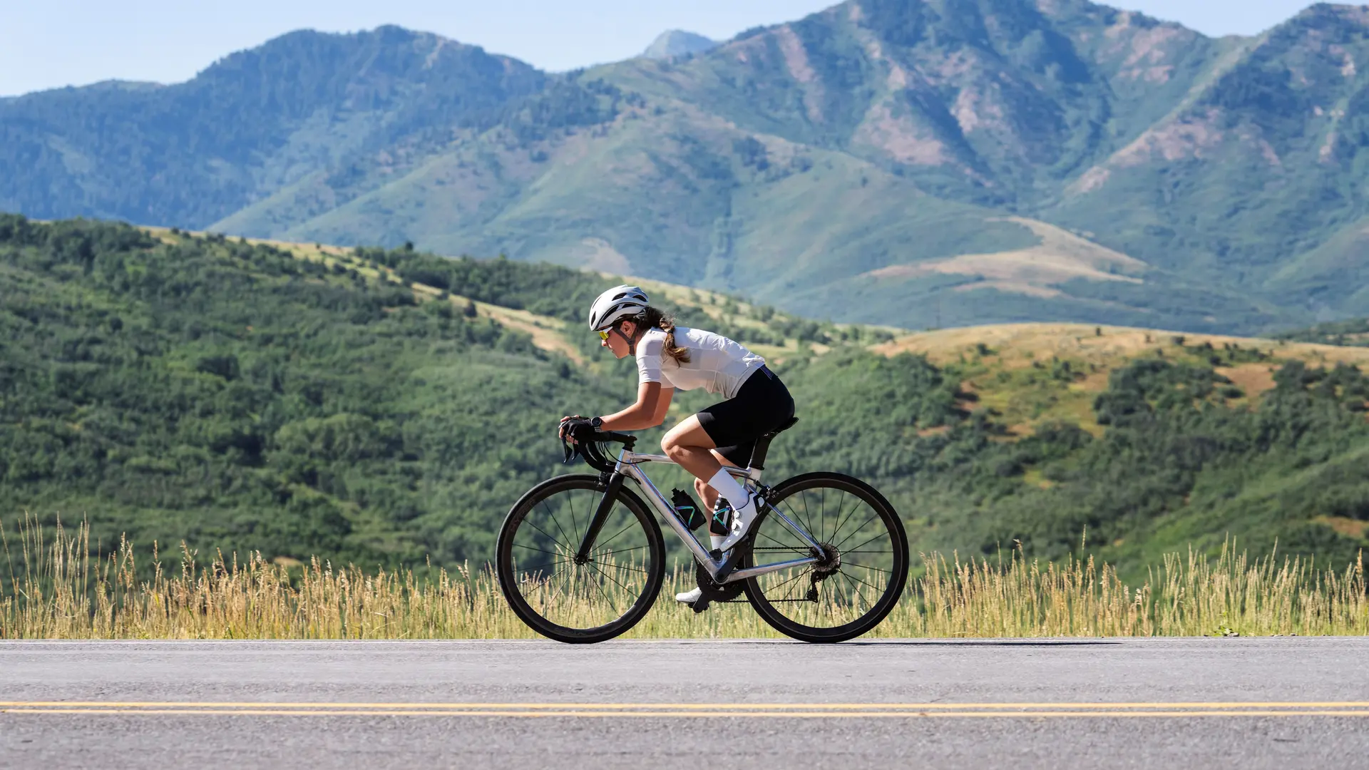 Femme Cycliste qui descend sur une route de montagne