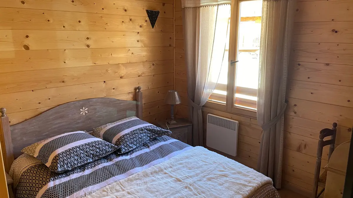 Bright bedroom with wooden furniture, panelling, double bed, window and curtains