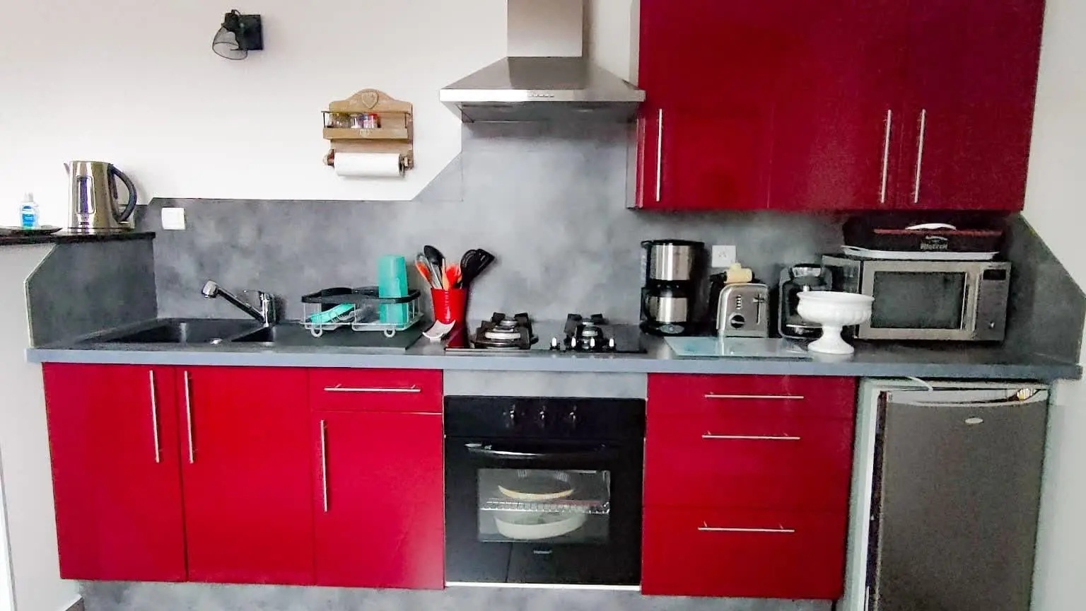 Cuisine fonctionnelle avec four, plaques de cuisson, cafetière et rangements.