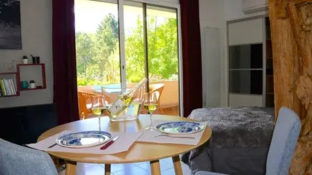 Le studio se compose d'une pièce principale avec une table de salle à manger, des chaises, un lit et une porte-fenêtre donnant sur une terrasse extérieure.