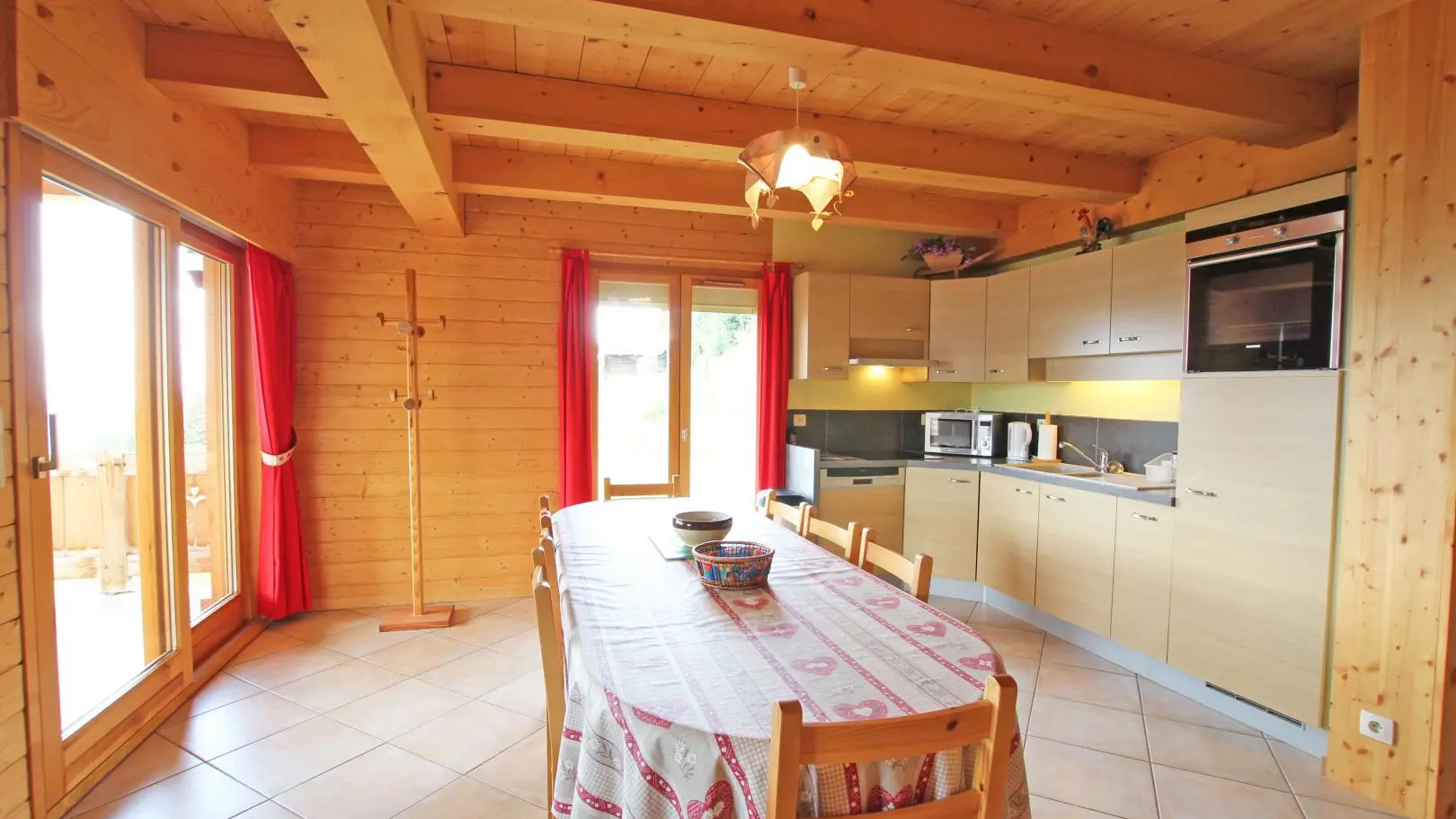 coin repas avec ouverture baie vitrée et porte fenêtre sur terrasse abritée et terrain.
