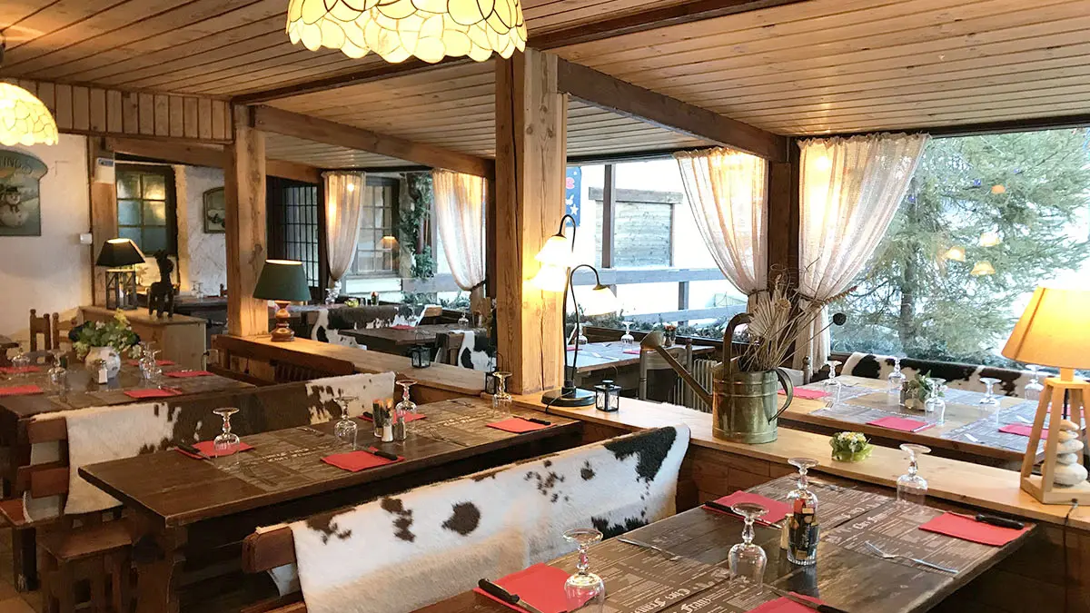 Salle intérieure du restaurant, tables et chaises, ambiance chalet et décor de montagne