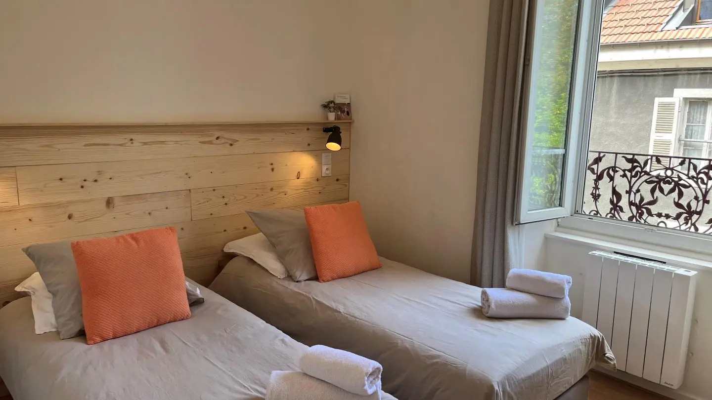 Chambre lumineuse équipée de deux lits simples.